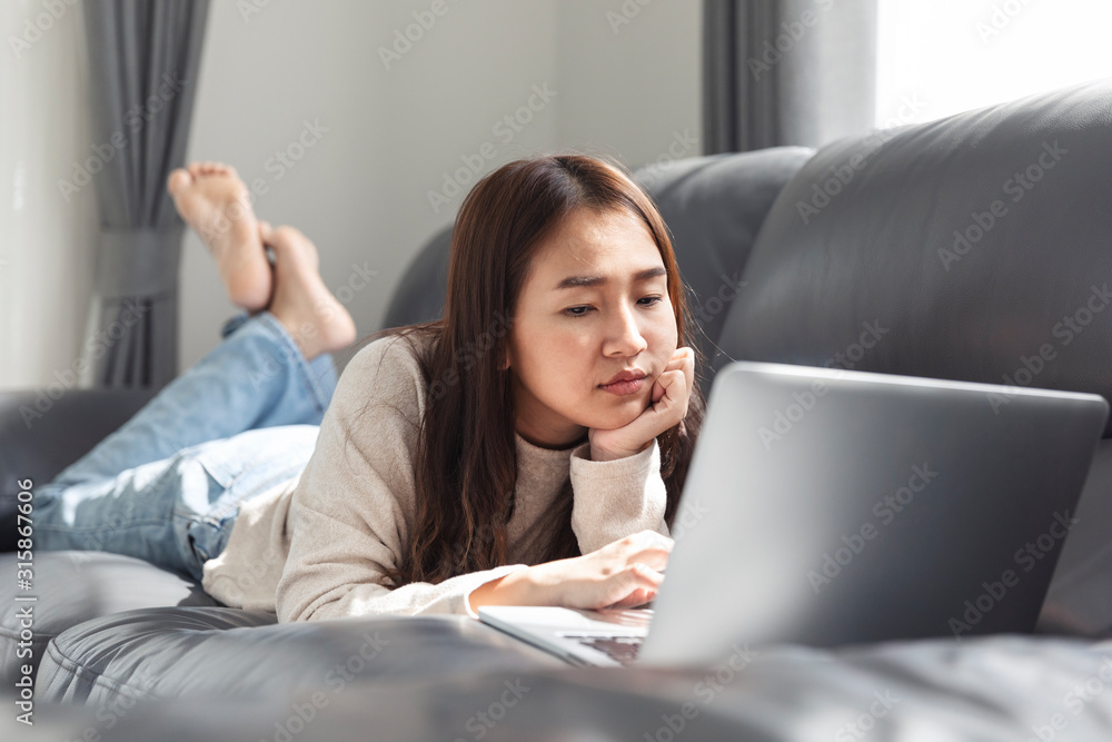 Young woman doing research work for her business, Smiling woman on sofa relaxing while browsing online shopping website. Young woman doing research work for her business, Smiling woman on sofa relaxing while browsing online shopping website.