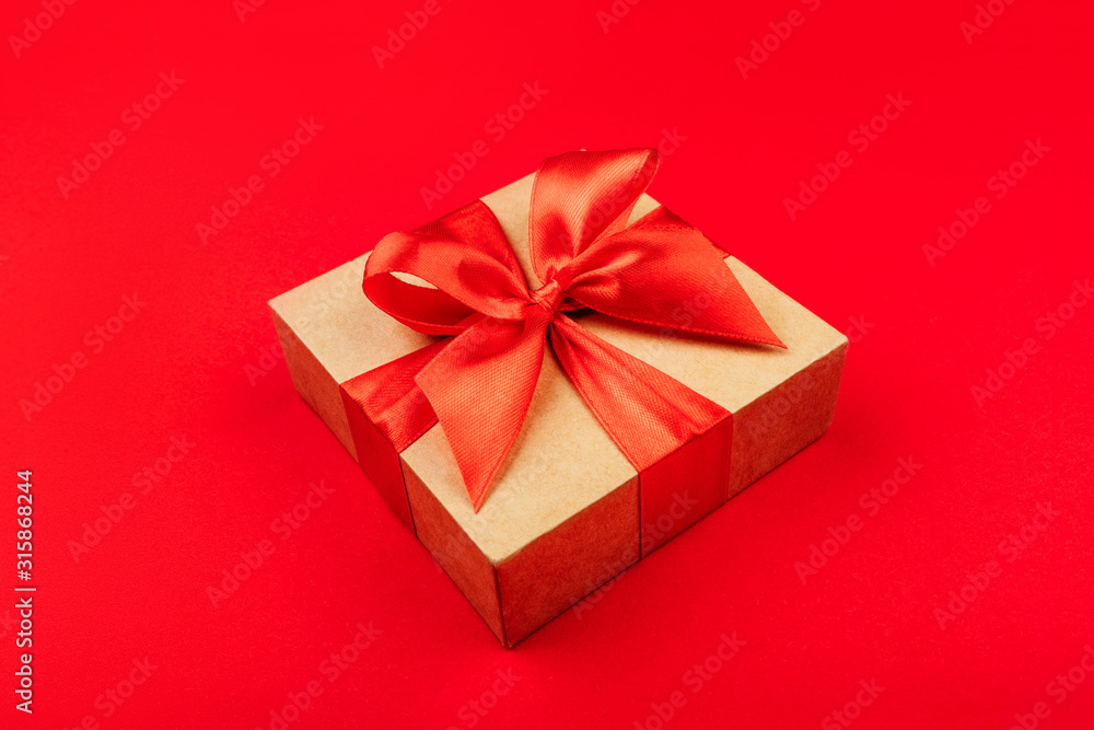 One cardboard gift box with bow on red background. One cardboard gift box with bow on red background.
