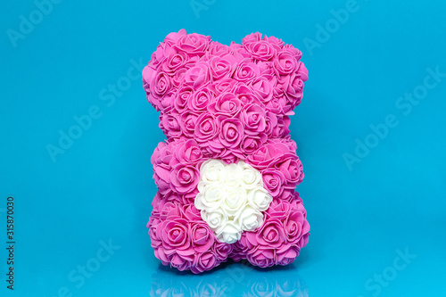 Pink bear, toy with white hearts on blue background. photo