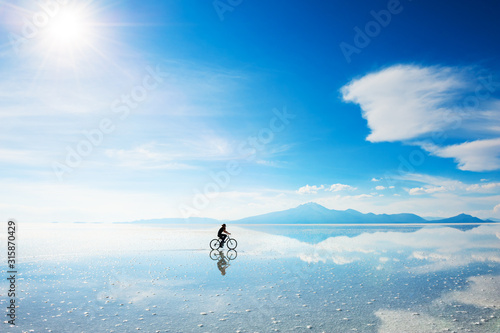 Woman riding a bicycle on the Salar de Uyuni salt flat in Bolivia. South America landscapes photo