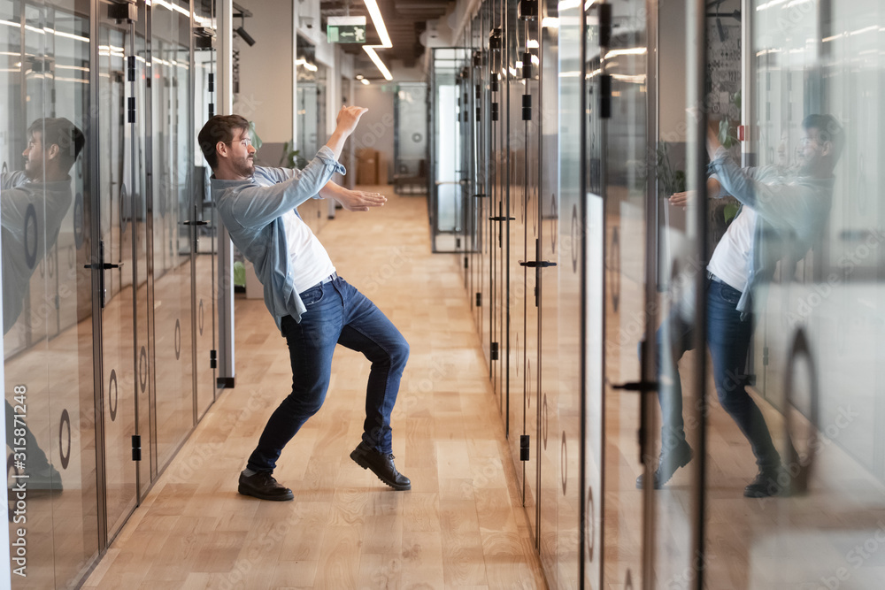 Obraz premium Funny millennial male dancing in hallway celebrating success