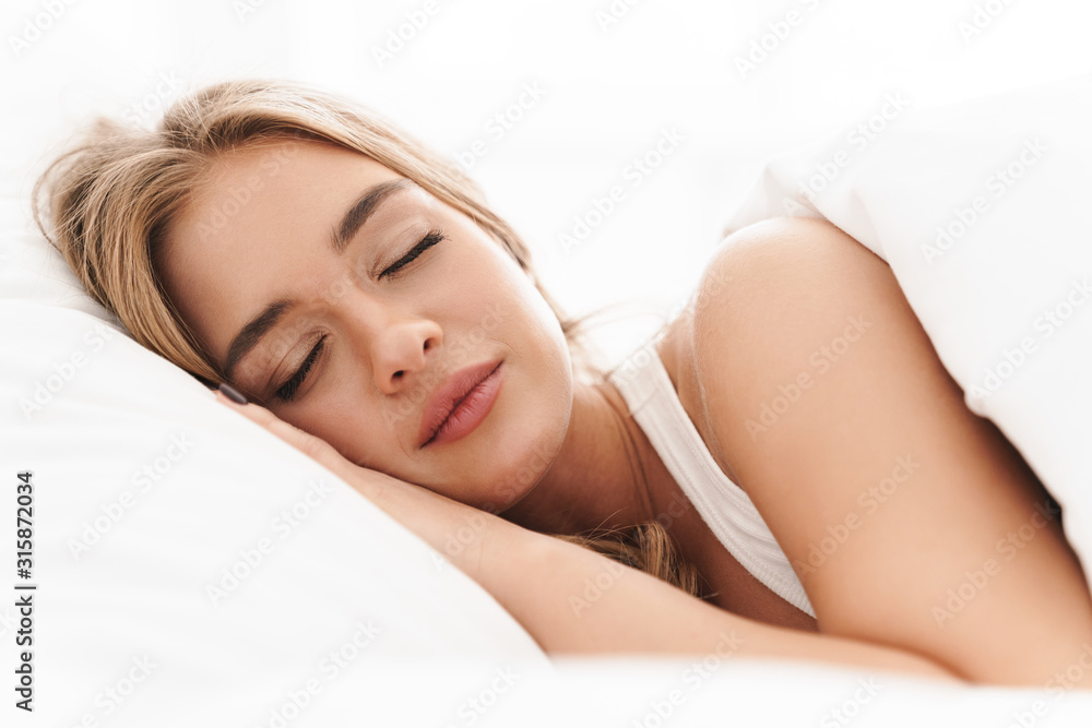 Photo of young caucasian woman sleeping while lying in bed