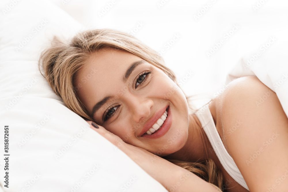 Photo of joyful caucasian woman smiling and while lying in bed Photo of joyful caucasian woman smiling and while lying in bed