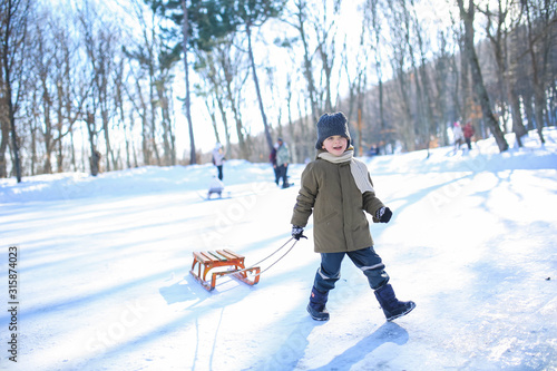 Boy sledding on the street in the snowy winter in the mountains.