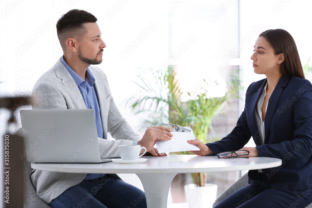 Obraz premium Woman giving bribe to man at table indoors