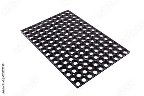 Black rubber entrance mat isolated on white background. Cellular rubber mat for dirt removal. Welcome carpet, close up