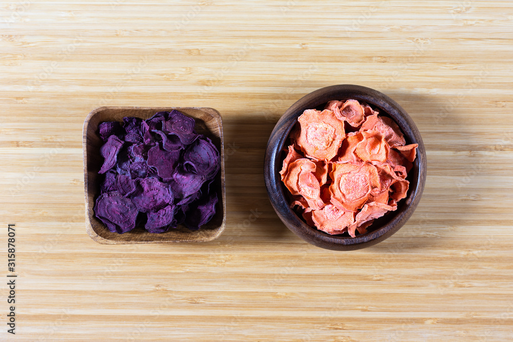 Dried carrot and beet chips in a wooden bowl on a cutting Board. Organic natural food