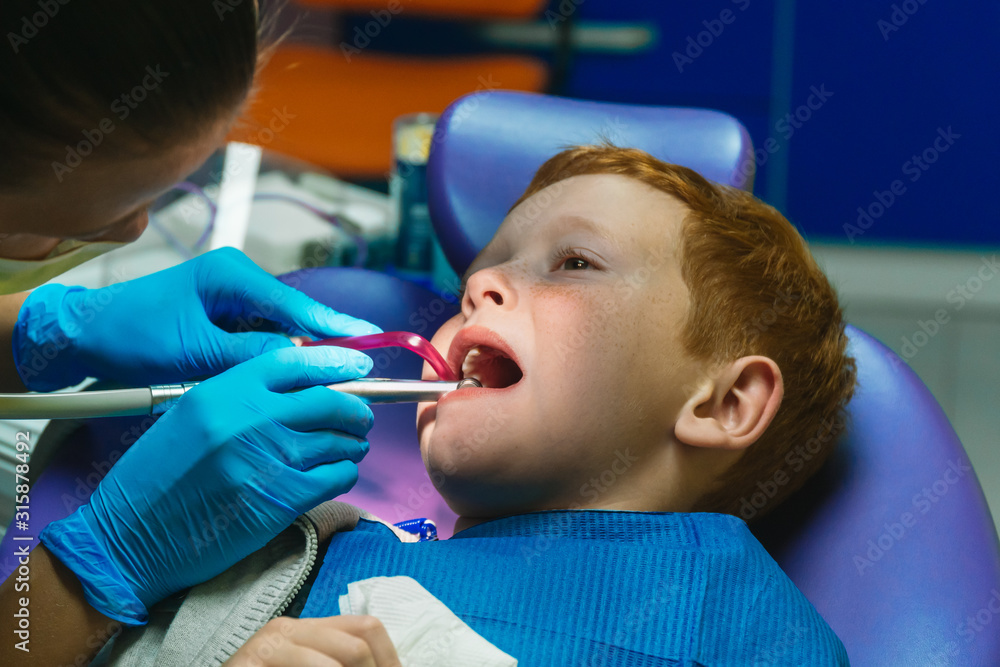 Scared red-haired boy crying at reception at dentist in dental chair. Pediatric dentistry Scared red-haired boy crying at reception at dentist in dental chair. Pediatric dentistry
