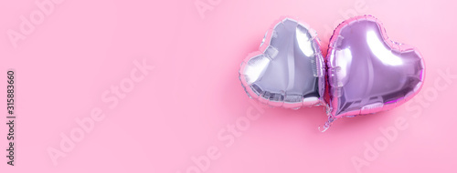 Valentine's Day minimal design concept - Beautiful real heart shape foil balloon isolated on pale pink background, top view, flat lay, overhead above photography.