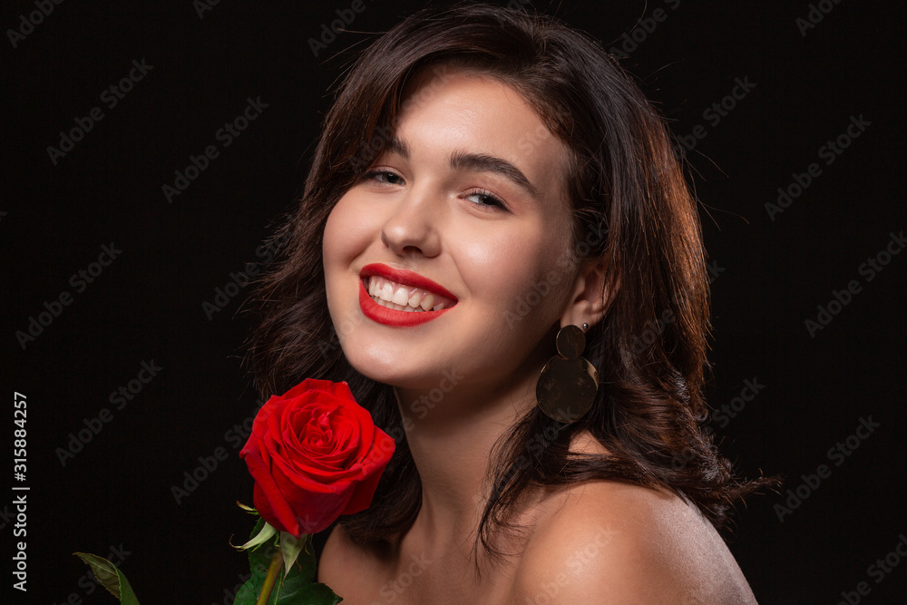 Beautiful woman with bright makeup posing isolated over black background with red rose. Beautiful woman with bright makeup posing isolated over black background with red rose.