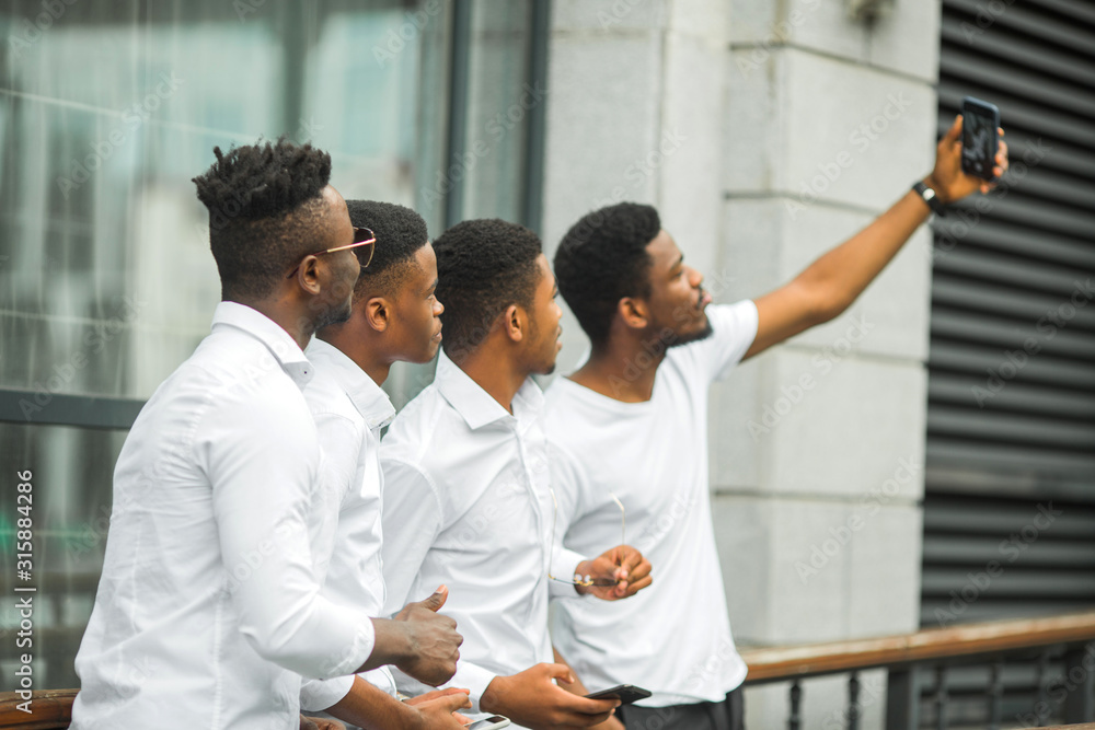 four handsome young african men in white shirts are photographed on the phone four handsome young african men in white shirts are photographed on the phone