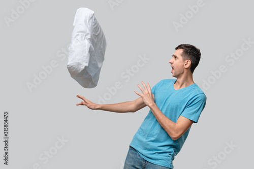 White pillow flying suddenly into pretty brunet man. photo