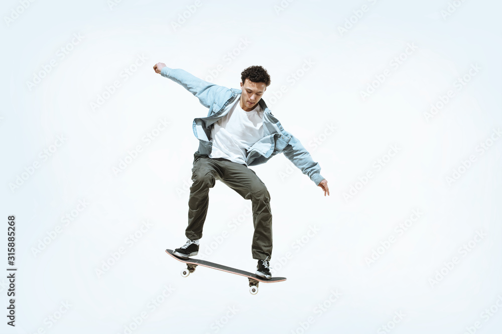 Caucasian young skateboarder riding isolated on a white studio background. Man in casual clothing training, jumping, practicing in motion. Concept of hobby, healthy lifestyle, youth, action, movement. Caucasian young skateboarder riding isolated on a white studio background. Man in casual clothing training, jumping, practicing in motion. Concept of hobby, healthy lifestyle, youth, action, movement.