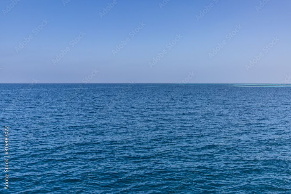Calm sea ocean and blue sky background. Endless view with horizon and blue tones Calm sea ocean and blue sky background. Endless view with horizon and blue tones