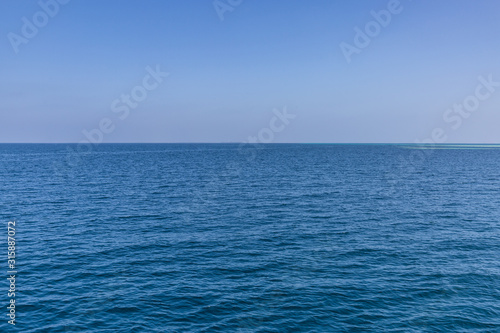 Calm sea ocean and blue sky background. Endless view with horizon and blue tones
