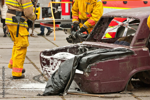 Demonstration of rescue work. Firefighters break into a car after an accident. Rescue team retrieve the victim from the burned car. Training firefighters.