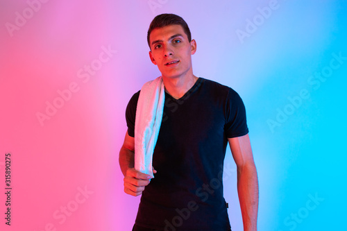 Portrait of a sports man with a towel around his neck, on a bright neon background