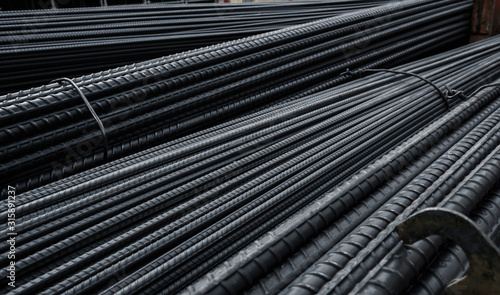 Building armature in the warehouse of metallurgical products or on construction site. Stack of heavy metal reinforcement bars with periodic profile texture. Steel construction armature.