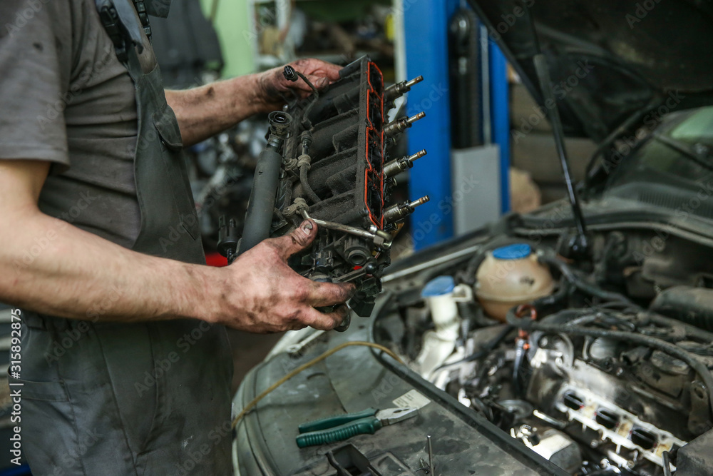 mechanic holds dismantled part of car engine in technical center mechanic holds dismantled part of car engine in technical center