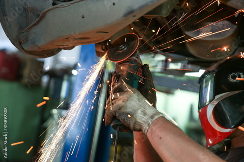 Schilderij op canvas cutting metal part with sparks in car service station close up
