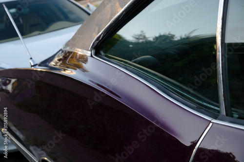 Rear window and curvy door details of a purple classic american car