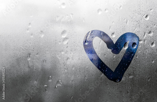 Heart painted on glass is fogged up and there are many drops on it