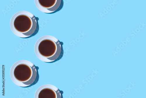 Frame of cups of black coffee or tea on a blue background. Flat lay, top view. Copy space for text.
