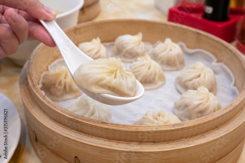 Photography Xiao long bao soup dumpling buns with chopsticks in restaurant (Traditional Chin