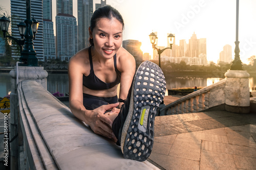 Asian woman strechting before workout during the sunrise in the city photo