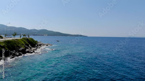 Drone aerial shot of small wooden fishing boat in crystal clear blue waters of Greece coastline.