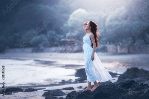 Free happy woman on beach enjoying nature. Natural beauty girl outdoor in freedom enjoyment concept. Mixed race Caucasian Asian girl posing on travel vacation holidays in dress.
