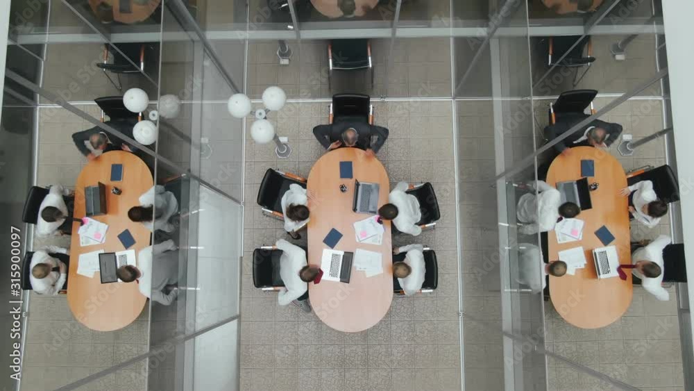 Top view. Colleagues office workers enter office space meeting room and sit at the table. Business partners come and prepare for negotiations and presentations on flipchart