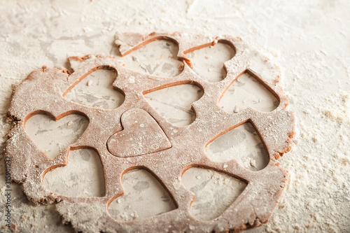 The process of making gingerbread. Flat lay flour heart dough. Texture of the dough for cookies close-up. Gingerbread dough on February 14, flour, rolling pin and copy space.