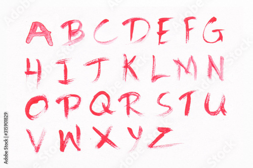 Letters A-Z with red watercolor on white paper background. Handwritten alphabet.