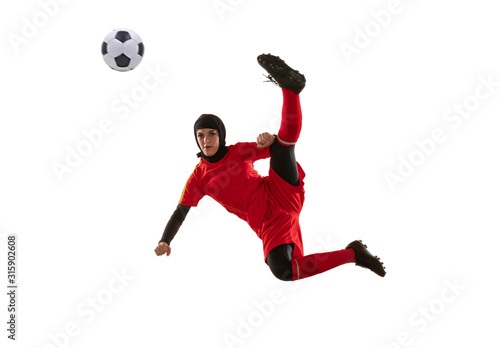 Fototapeta Naklejka Na Ścianę i Meble -  Arabian female soccer or football player isolated on white studio background. Young woman kicking ball in jump, catched in air, training in motion, action. Concept of sport, hobby, healthy lifestyle.