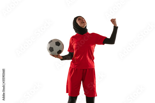 Emotions. Arabian female soccer or football player on white studio background. Young woman celebrating goal or match winning, catched in motion, action. Concept of sport, hobby, healthy lifestyle.