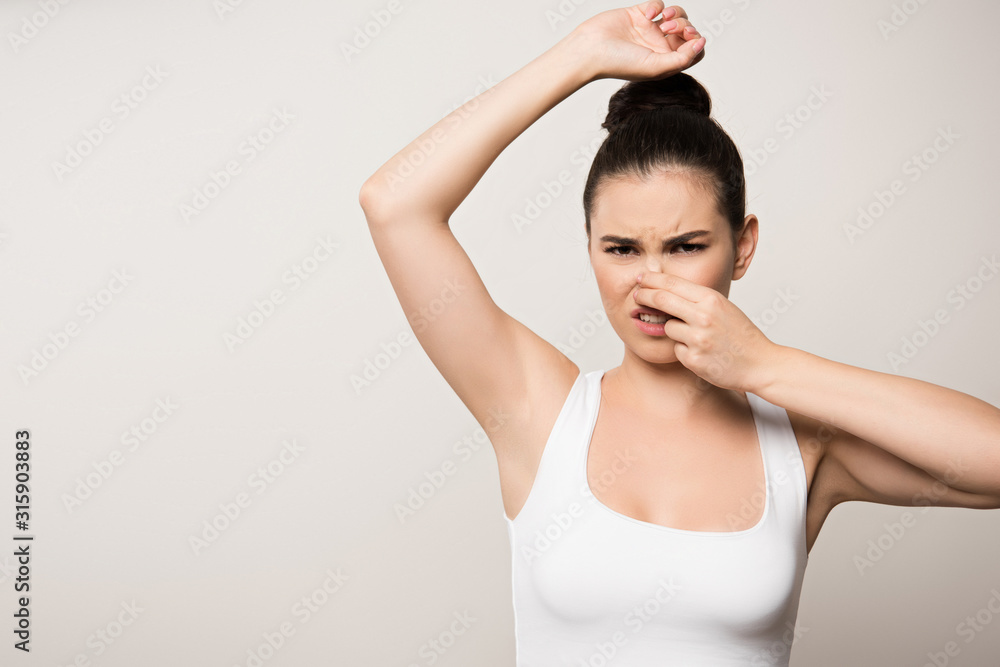 displeased woman plugging nose with hand while looking at camera isolated on grey displeased woman plugging nose with hand while looking at camera isolated on grey