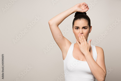 Bilde på lerret shocked woman covering mouth with hand while looking at camera isolated on grey