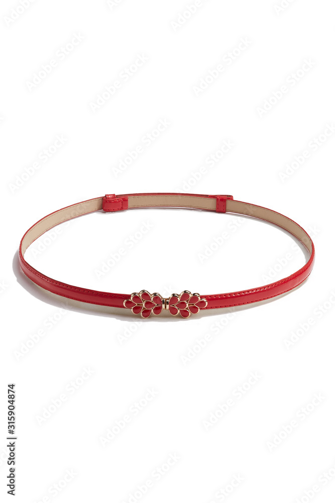 Subject shot of a thin belt made of red leather and decorated with a figured buckle in the form of golden drops with red jeweller's enamel. The stylish belt is isolated on the white background. Subject shot of a thin belt made of red leather and decorated with a figured buckle in the form of golden drops with red jeweller's enamel. The stylish belt is isolated on the white background.