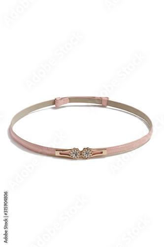 Subject shot of a thin belt made of pale pink patent leather and decorated with a golden figured buckle with crystal flowers. The stylish belt is isolated on the white background.