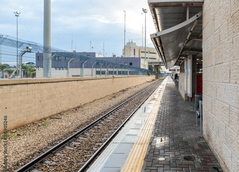 Several travelers await the train on the empty platform of the Mirkaz Shmona railway station in Haifa, Israel Several travelers await the train on the empty platform of the Mirkaz Shmona railway station in Haifa, Israel