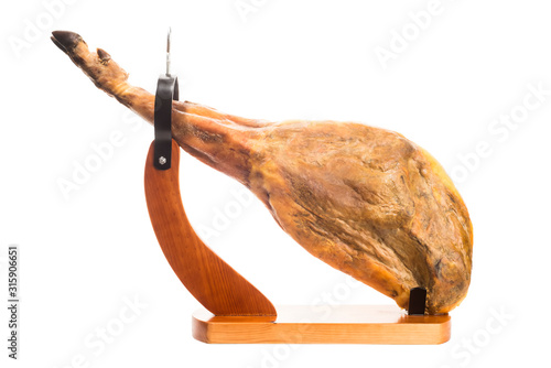 Whole Iberian ham leg in a wooden ham stand isolated photo