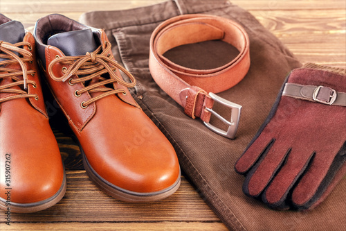 Trend men accessories, Leather boots, belt and pants, fashion set on wood floor.