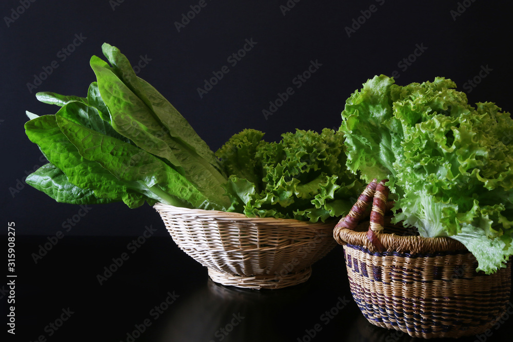 Due cesti su fondo nero con verdure fresche: cicoria e insalata lattuga Due cesti su fondo nero con verdure fresche: cicoria e insalata lattuga