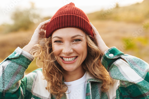 Canvas Print Image of young woman wearing hat and plaid shirt walking outdoors