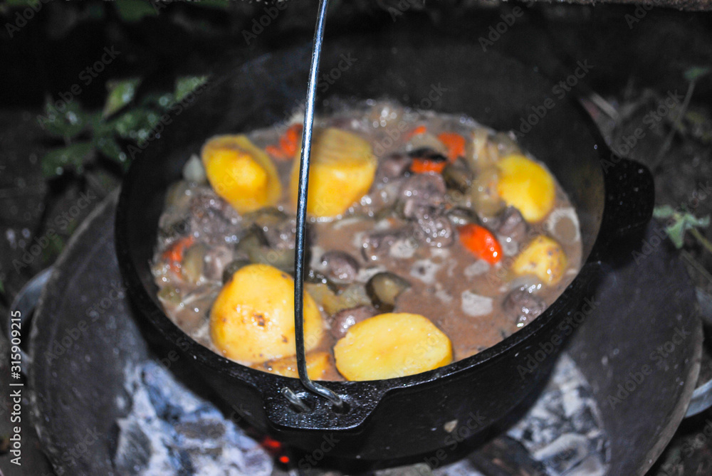 meat and offal with potatoes in a cauldron cooking on a camping trip meat and offal with potatoes in a cauldron cooking on a camping trip