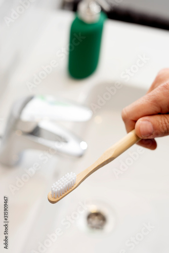 man using a bamboo toothbrush in the bathroom
