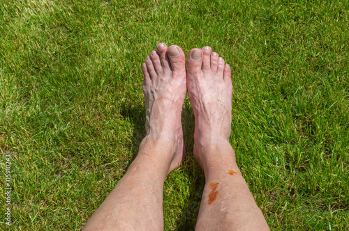 Elderly man's feet lying on a green lawn while resting after long bicycle trip