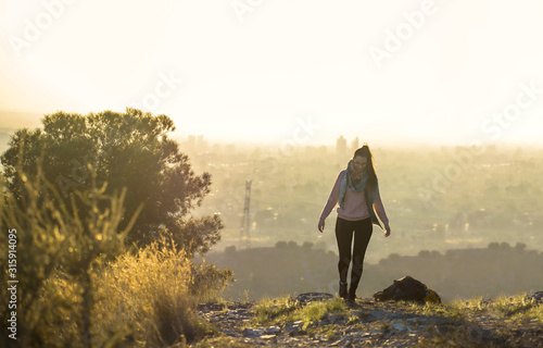 Sporty woman walking at the mountain top against foggy landscape and cityscape of Murcia in Spain. Adventurer hiking in countryside. Hobby. Copy space. photo