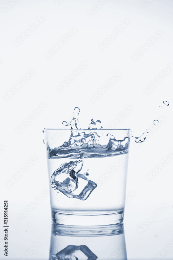 Clear mineral water splashes in a glass with ice. Clear mineral water splashes in a glass with ice.